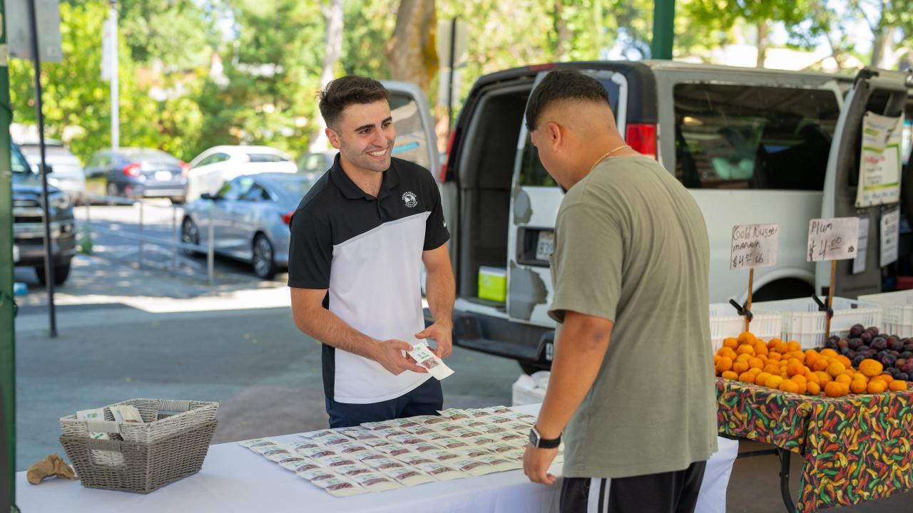 Dion Skaria, a food science major, sells his Fit Candy product at the Davis farmer's market. Photo by: Jael Mackendorf, UC Davis.