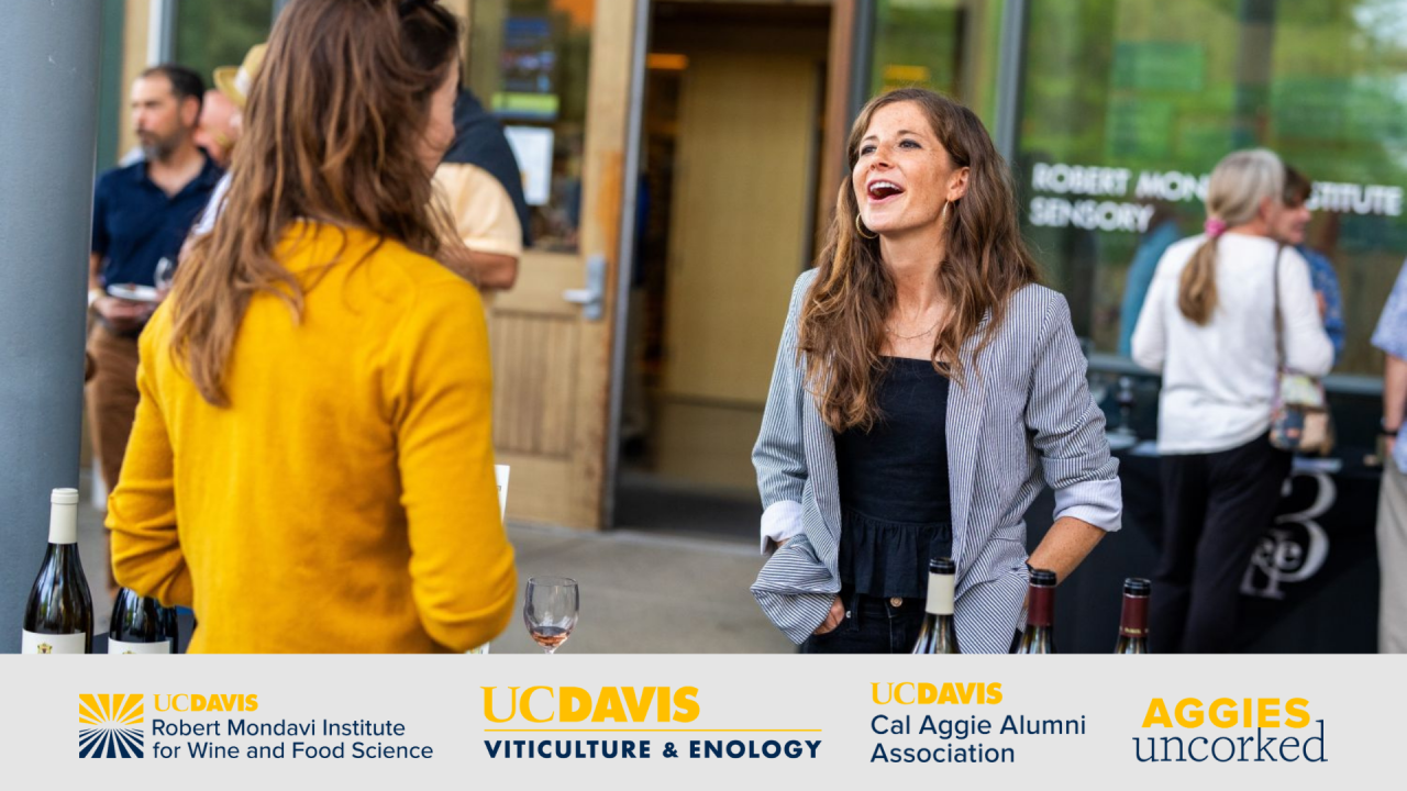 Two women are conversing outdoors, one in a yellow sweater and the other in a gray jacket.
