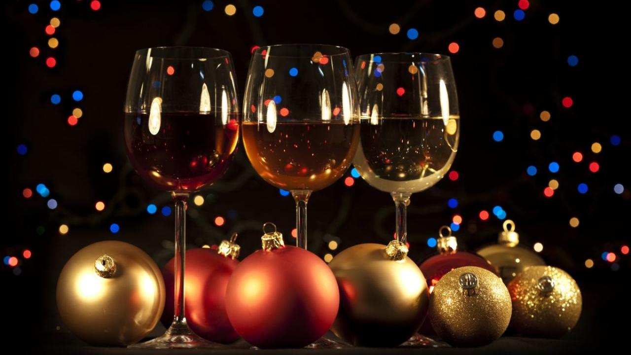 Glasses with red, rose and white wine in them with holiday ball ornaments in front and a dark background