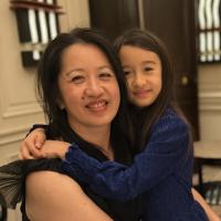 Smiling Chutharat Sae Tong and young girl hugging in warm indoor setting